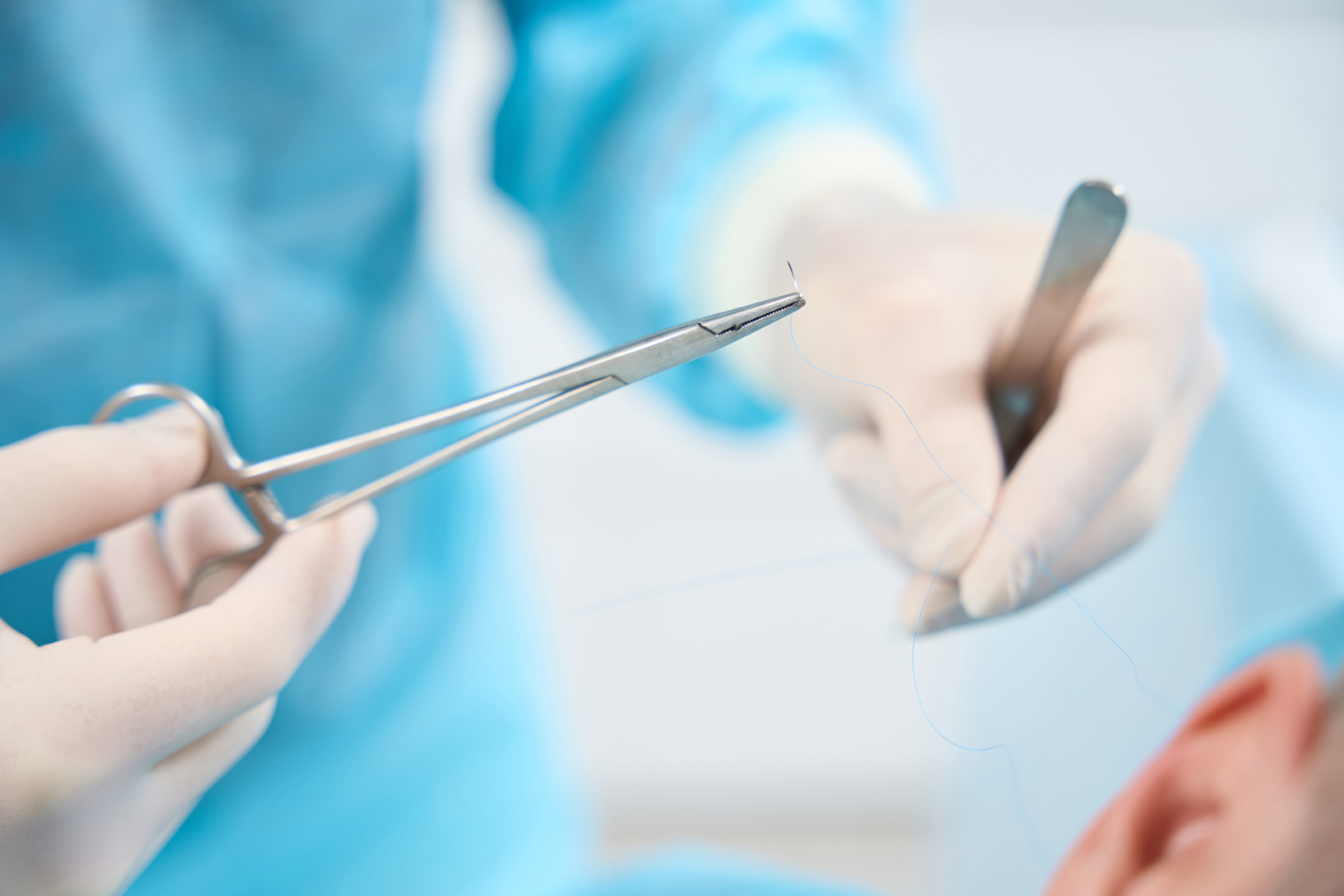 Close up of professional medic handling needle and thread for stitching