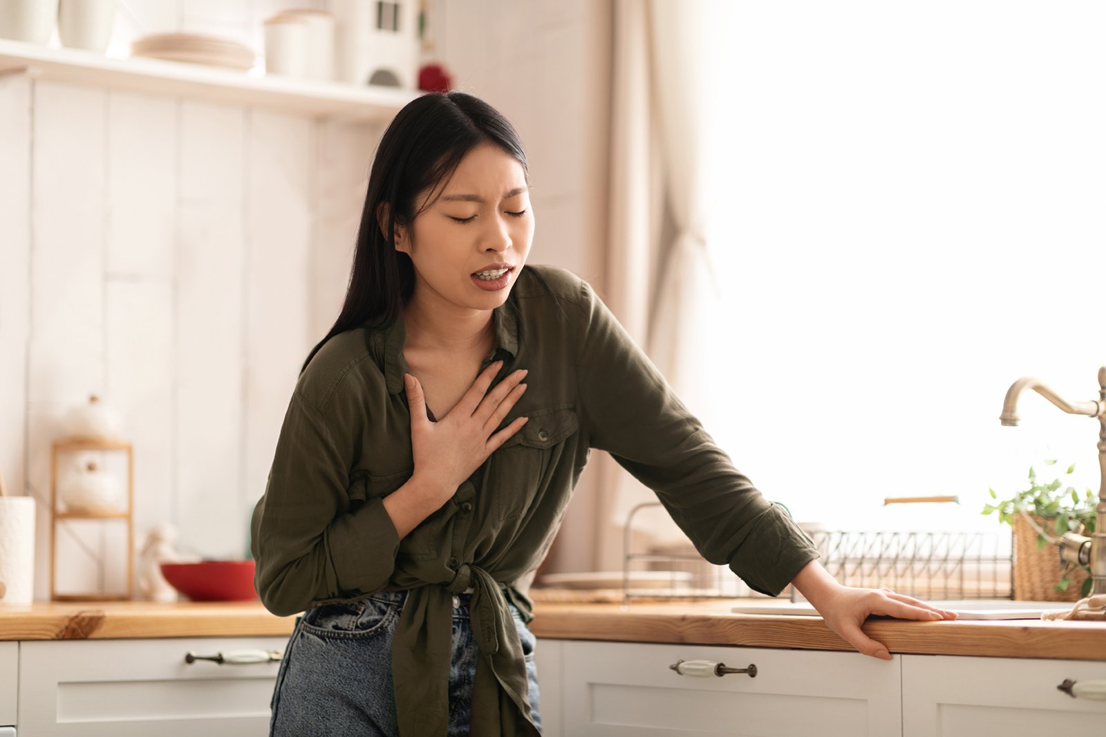 An Asian women heartburn in kitchen