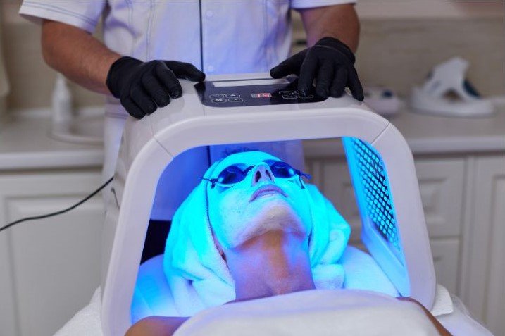 woman receiving blue light treatment to reduce acne
