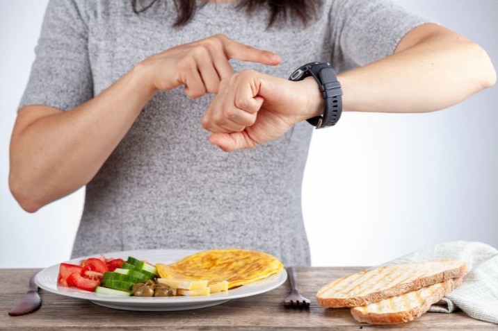 girl checking her wristwatch while there's food on the table